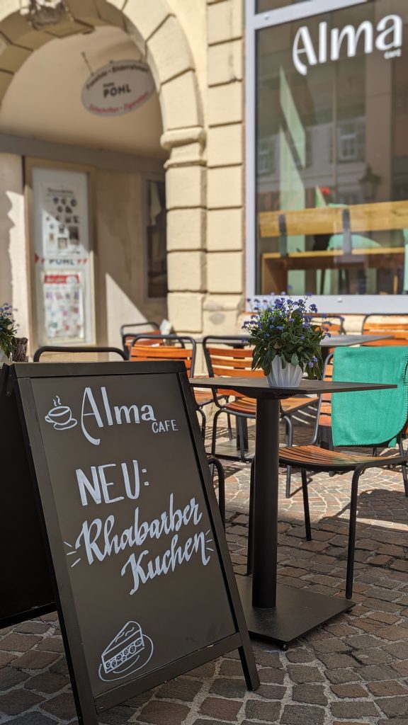 Café Alma Außenbereich Aufsteller Rhabarberkuchen